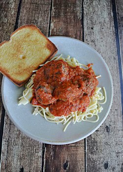 Spaghetti and meatballs with a slice of garlic bread.