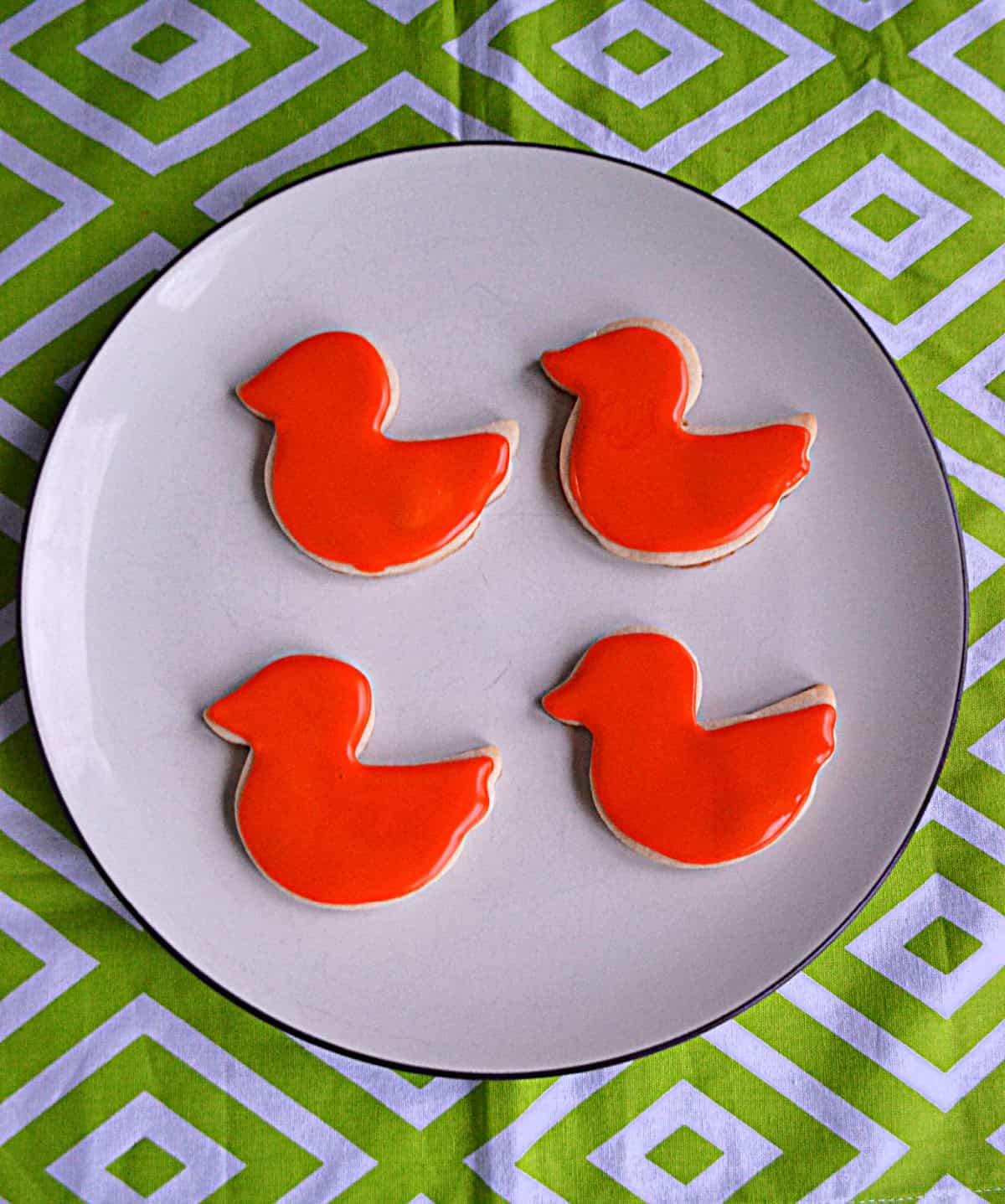 A plate of bird cookies with orange icing on them.