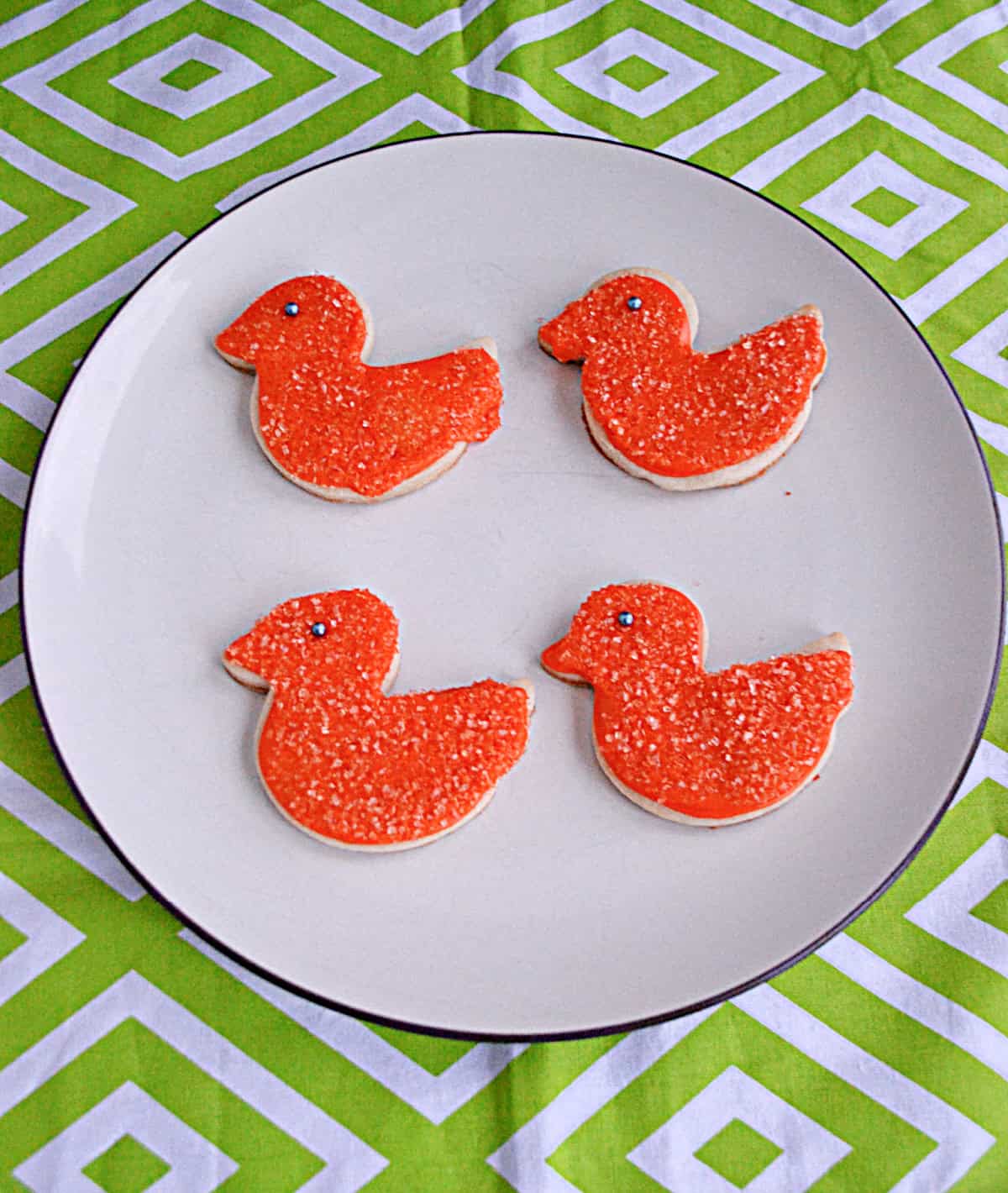 A plate of bird cookies with orange icing and sugar on them.