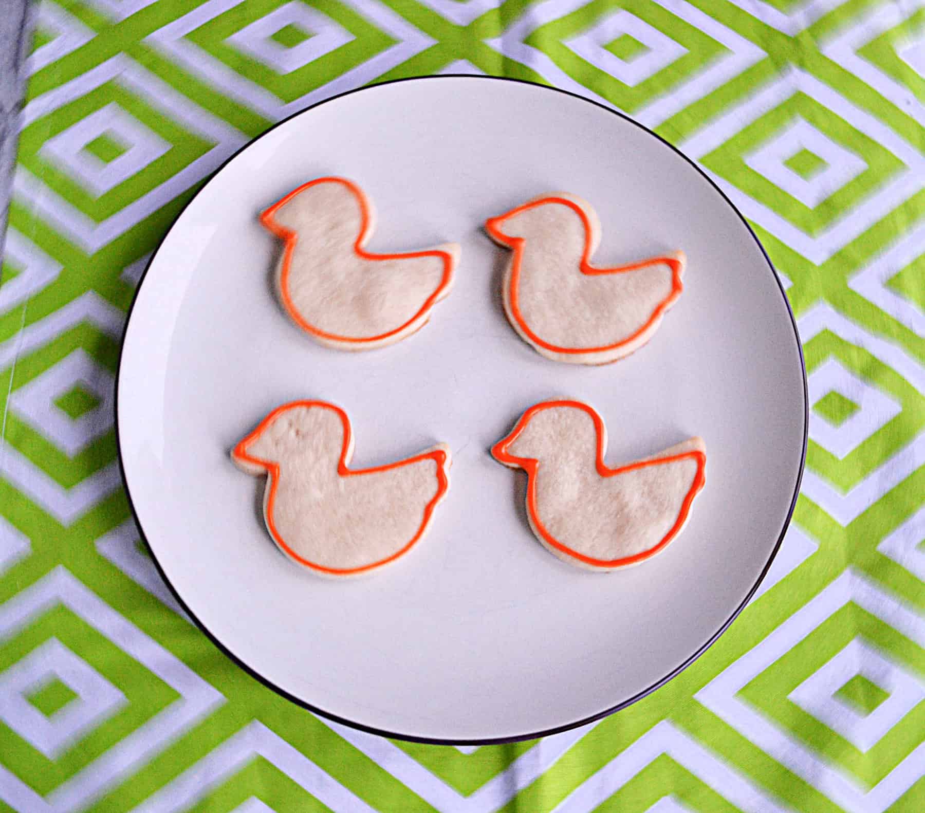 A plate with bird cookies on it and an orange icing outside on the cookies.