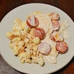 Pin Image: Text title, a plate of pierogi and kielbasa in a white sauce with cauliflower on the side, Get the recipe with a link.