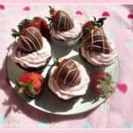 A plate with four cupcakes on it topped with chocolate covered strawberries