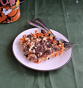 A plate with a piece of carrot cake oatmeal on it and 2 forks.