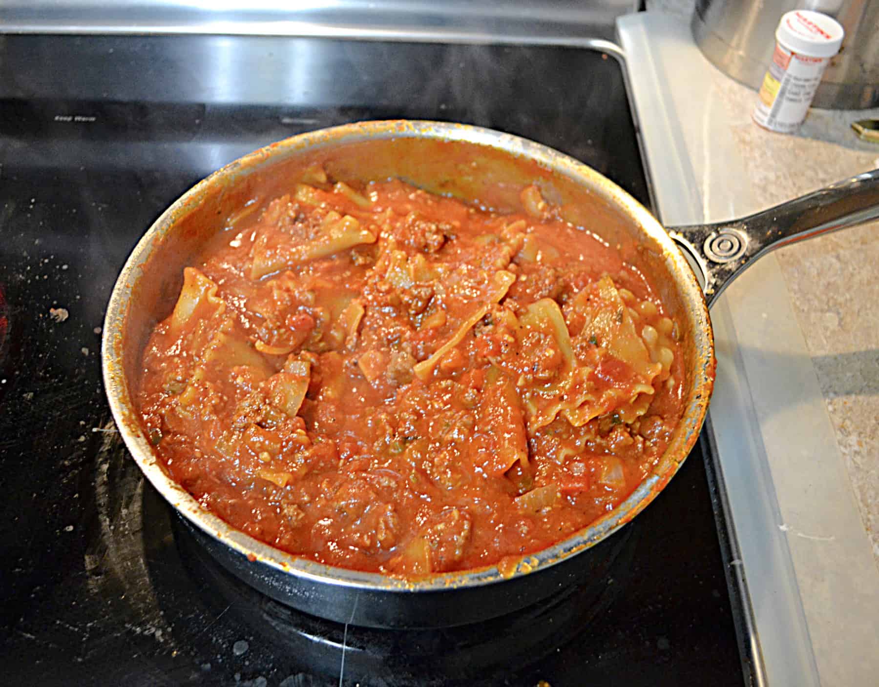 A skillet filled with tomato sauce, beef, and noodles.