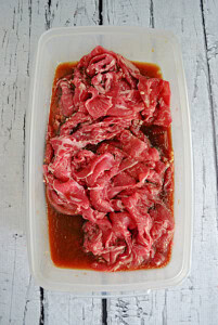 A container of beef in a marinade.