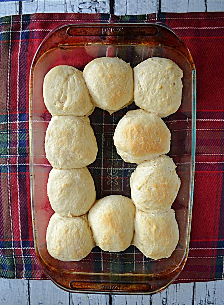 A glass baking dish with 10 cooked dinner rolls in it.