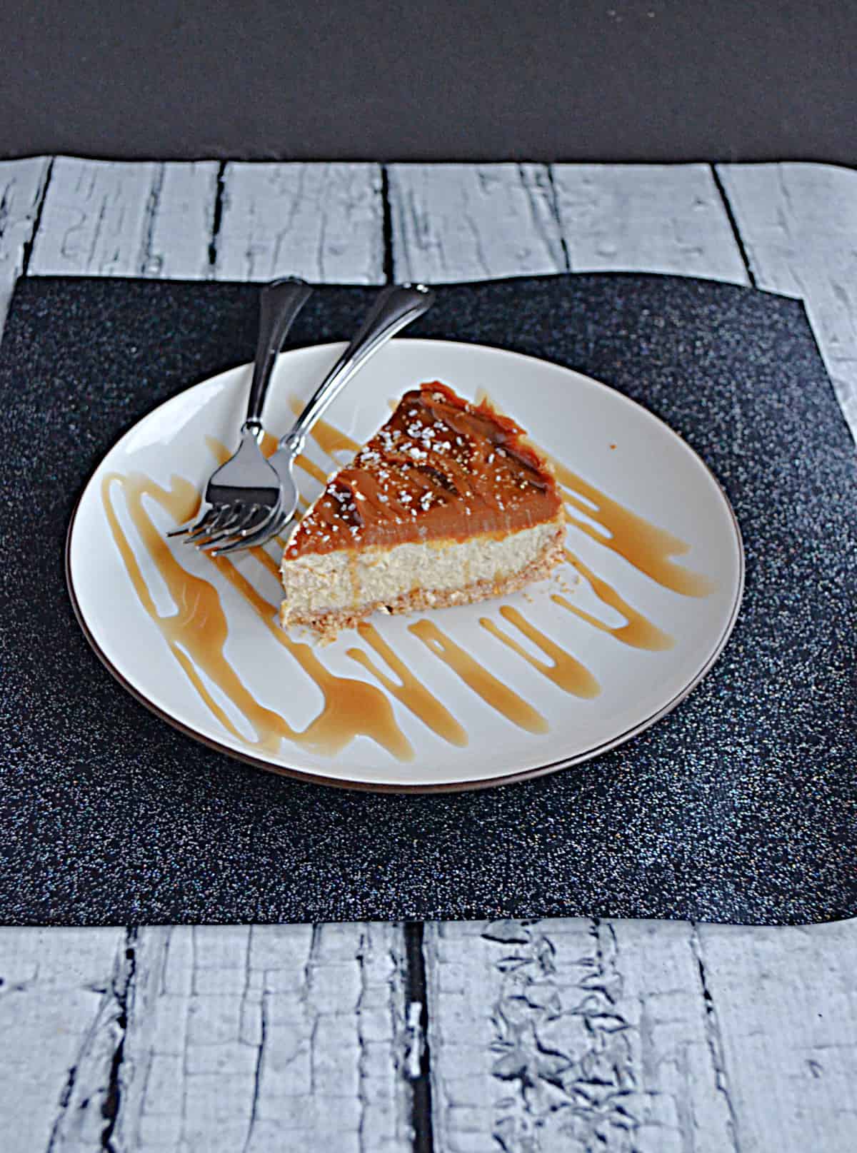 A plate with a slice of Dulce de Leche cheesecake and 2 forks on the plate.