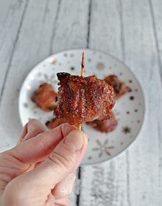 A hand holding a Bacon Wrapped Meatball on a toothpick.