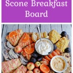 Pin Image: Text title, a board with scones, apples, fresh fruit, figs, and spreads on it.