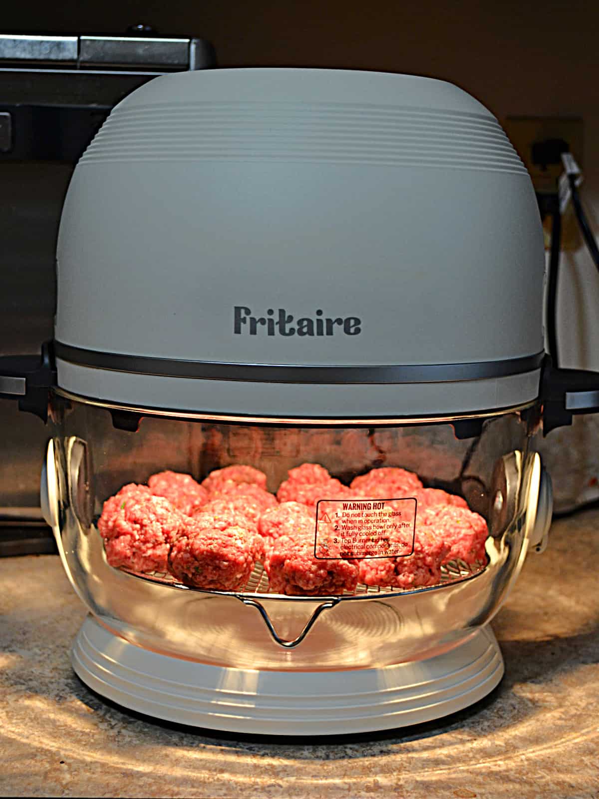 Meatballs cooking in a glass bowl air fryer.