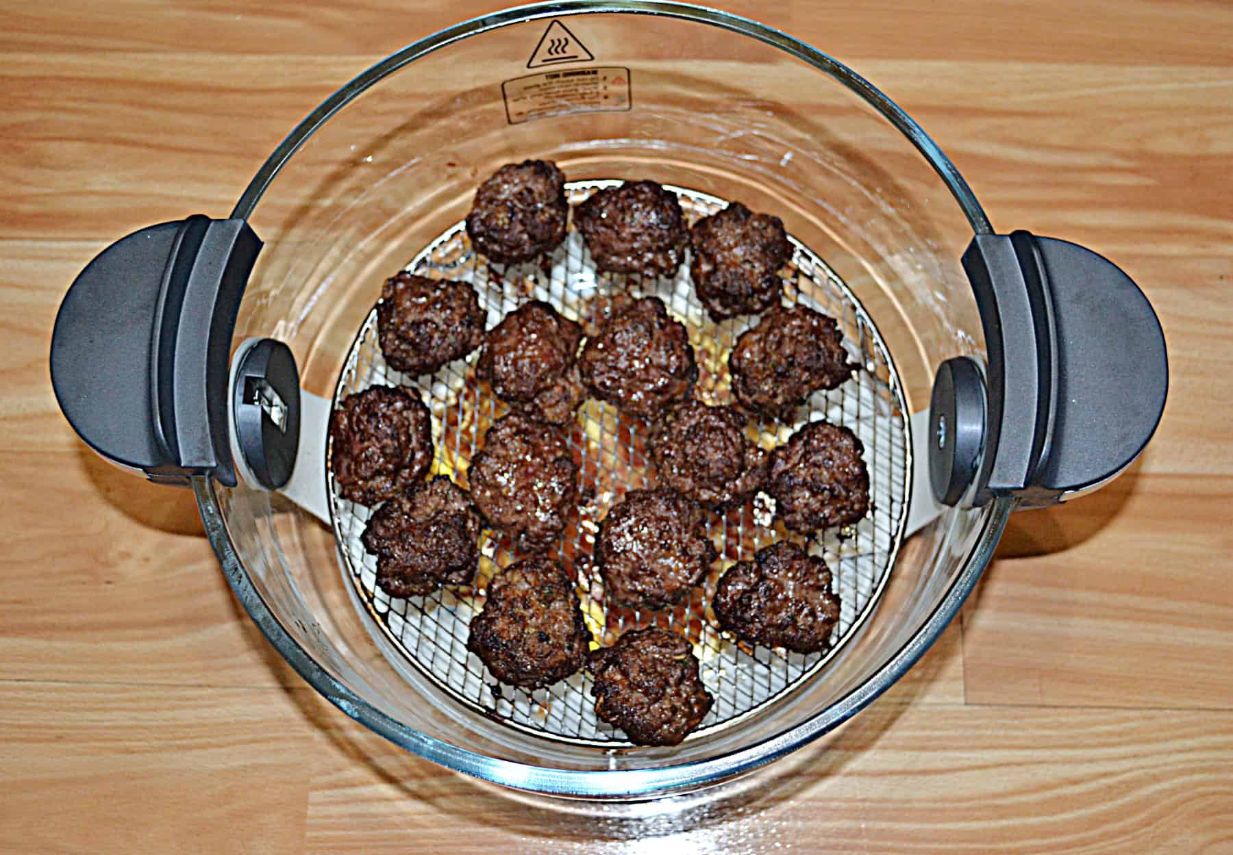 Cooked meatballs in the bowl of an air fryer.