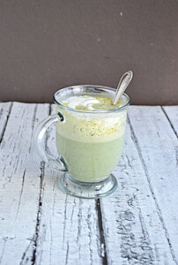A mug of green tea matcha latte with a spoon in it.