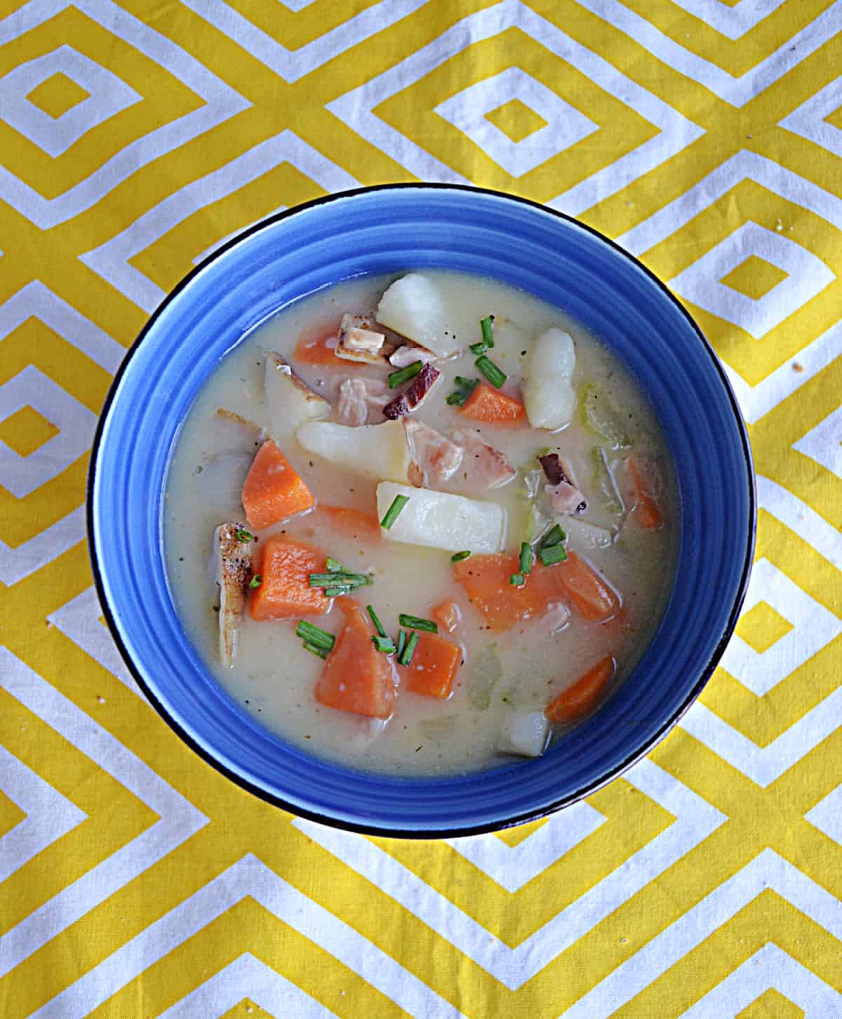 A bowl of ham and potato soup with vegetables.