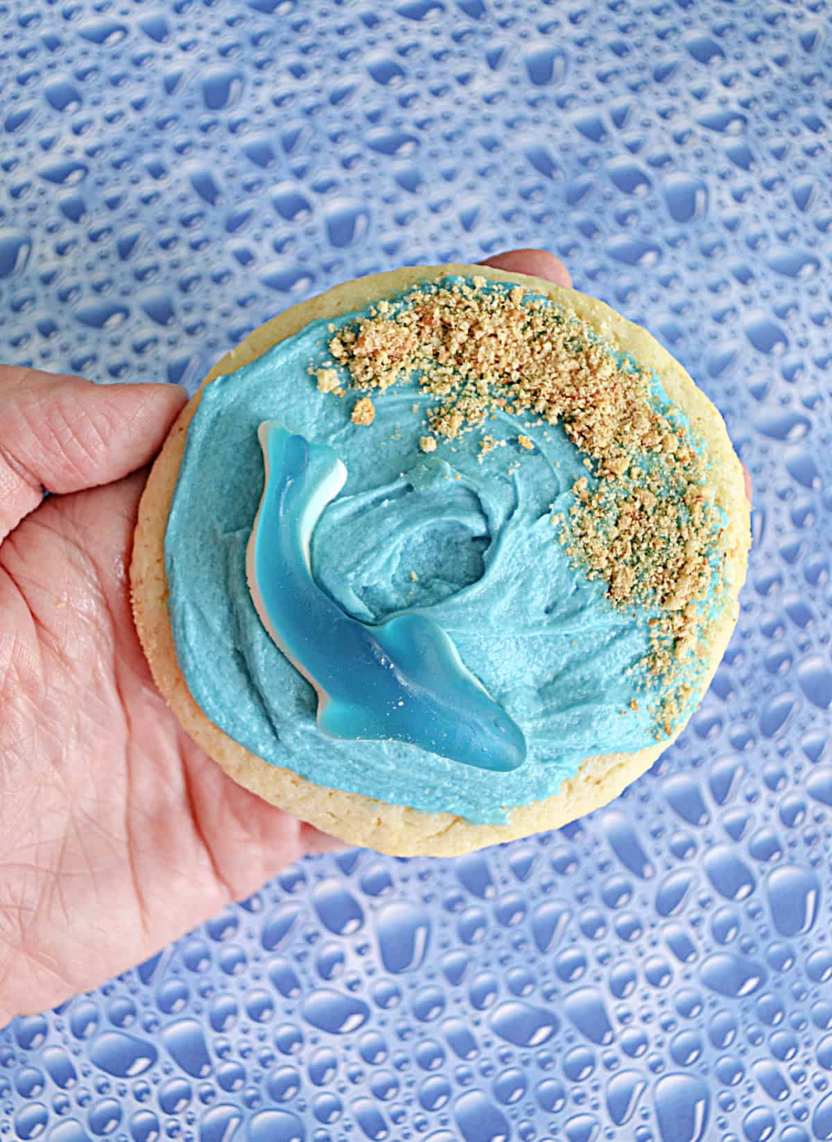 A hand holding a shark sugar cookie.