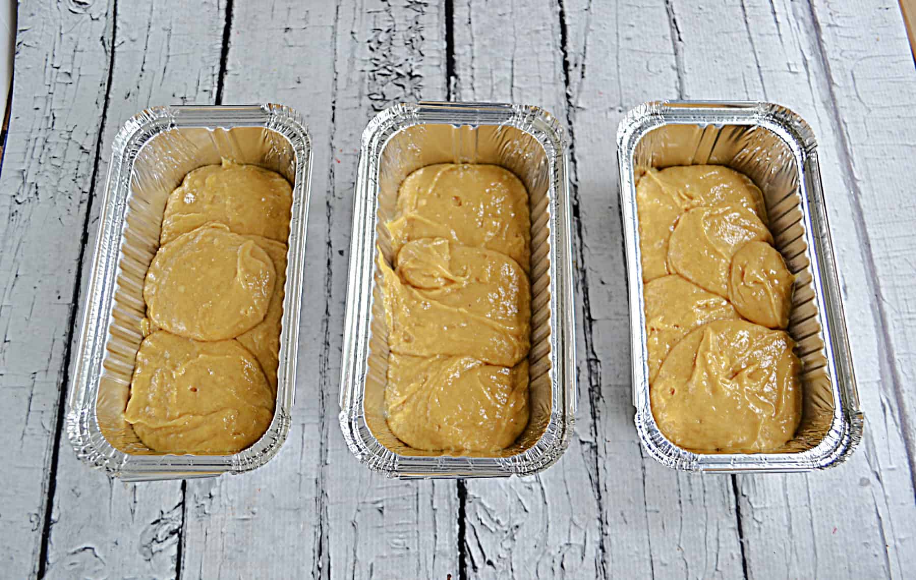 Three loaf pans with cake batter in them.