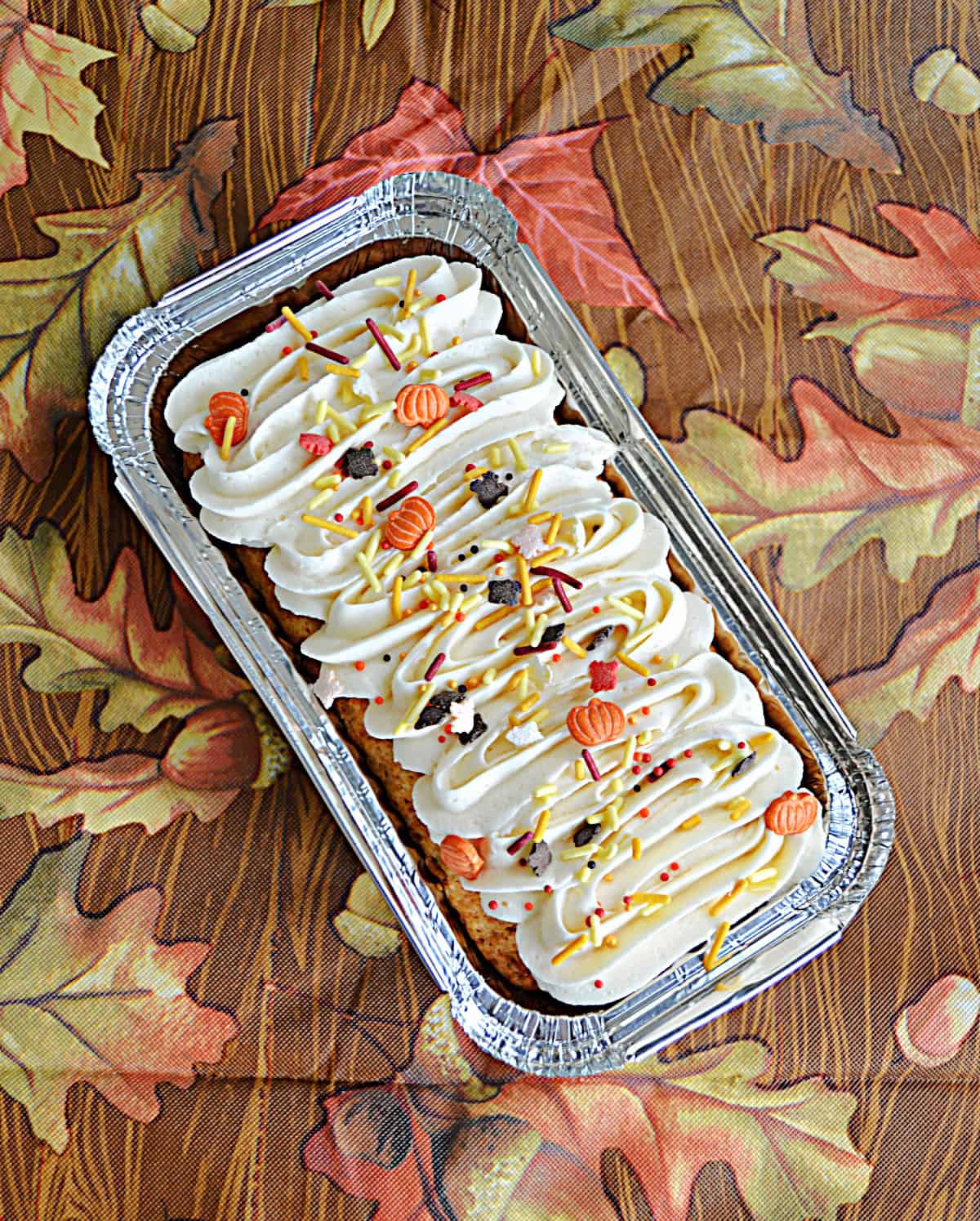 A pan of pumpkin loaf cake with frosting and sprinkles.