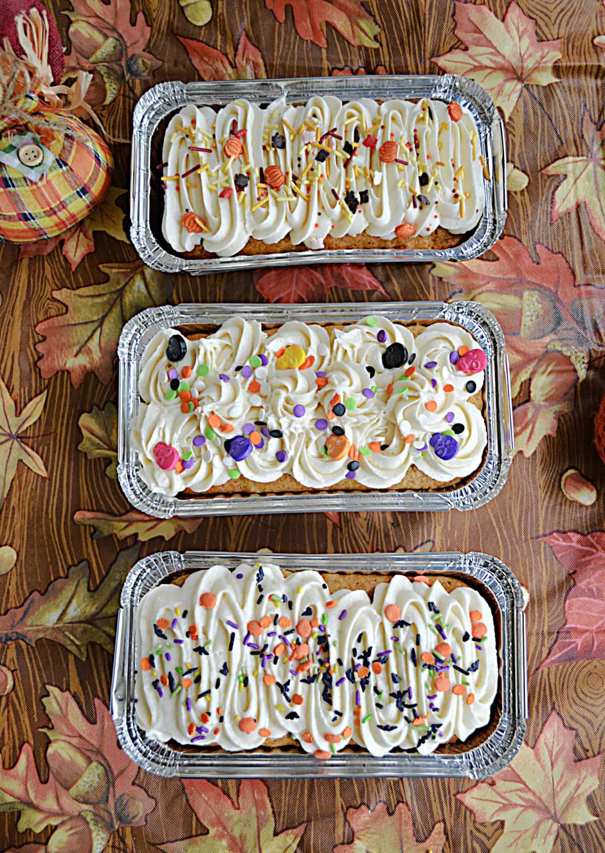 Three loaf pans with cake and frosting in them. 