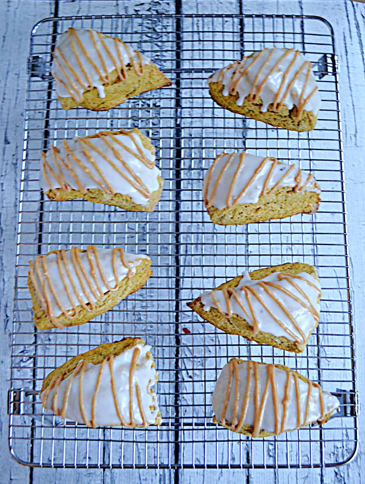 A wire rack with glazed scones on top of it.